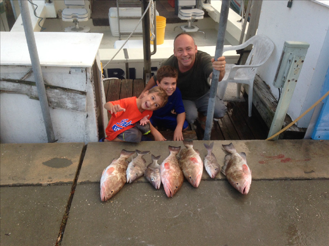 A father and sons posing with the fishes