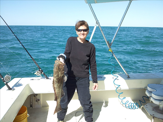 A woman holding a brown color fish on the boat